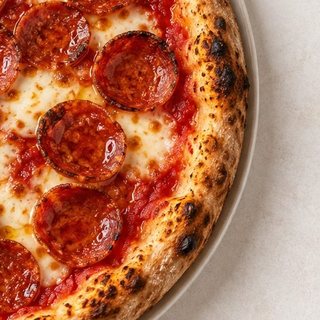The blistered, leopard-spotted rim of a Pepperoni pizza